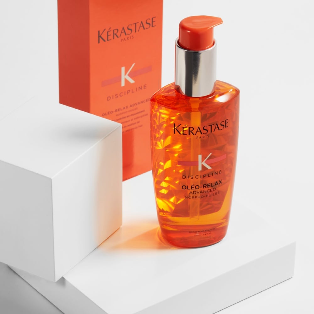 Discipline Oléo-Relax hair oil is displayed on a pure grey background with cubes. The hair oil controls frizz, moisturizes hair and suppress its volume.